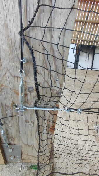 Fixation de filet de volière sur poutre en bois de hangar avec câble