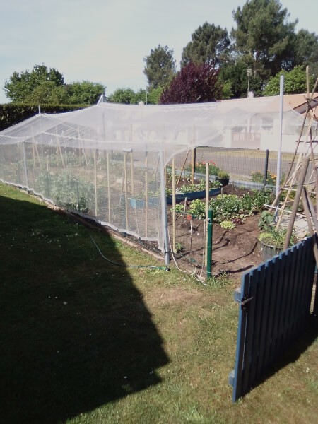Filet anti-grêle blanc tendus sur structure destiné à protéger un potager