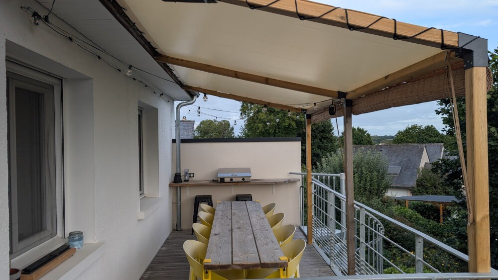 Bâche d'ombrage en toit de pergola en bois adossée maison