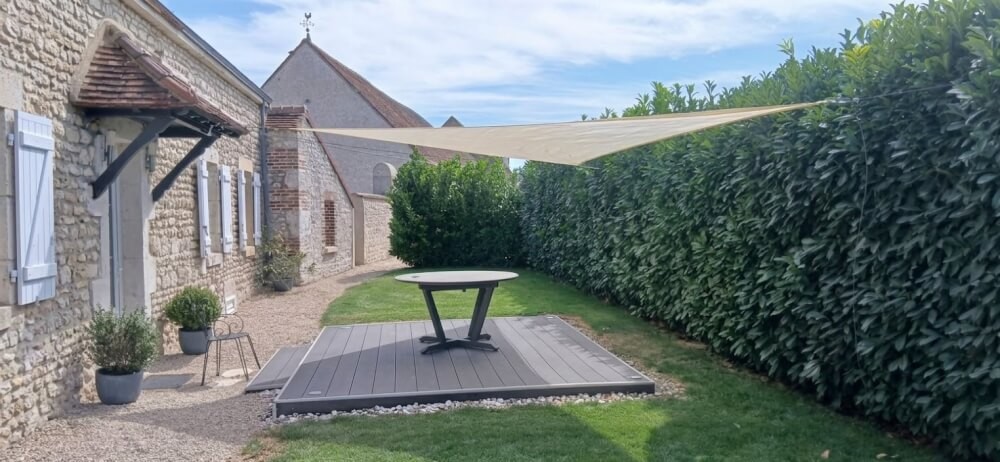 Installation d'une toile d'ombrage pour un espace repas dans jardin