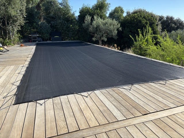 Filet anti-feuilles de piscine fixé sur terrasse en bois