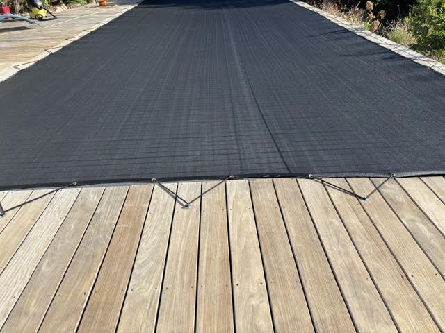 Filet anti-feuilles noir de piscine fixé sur terrasse en bois