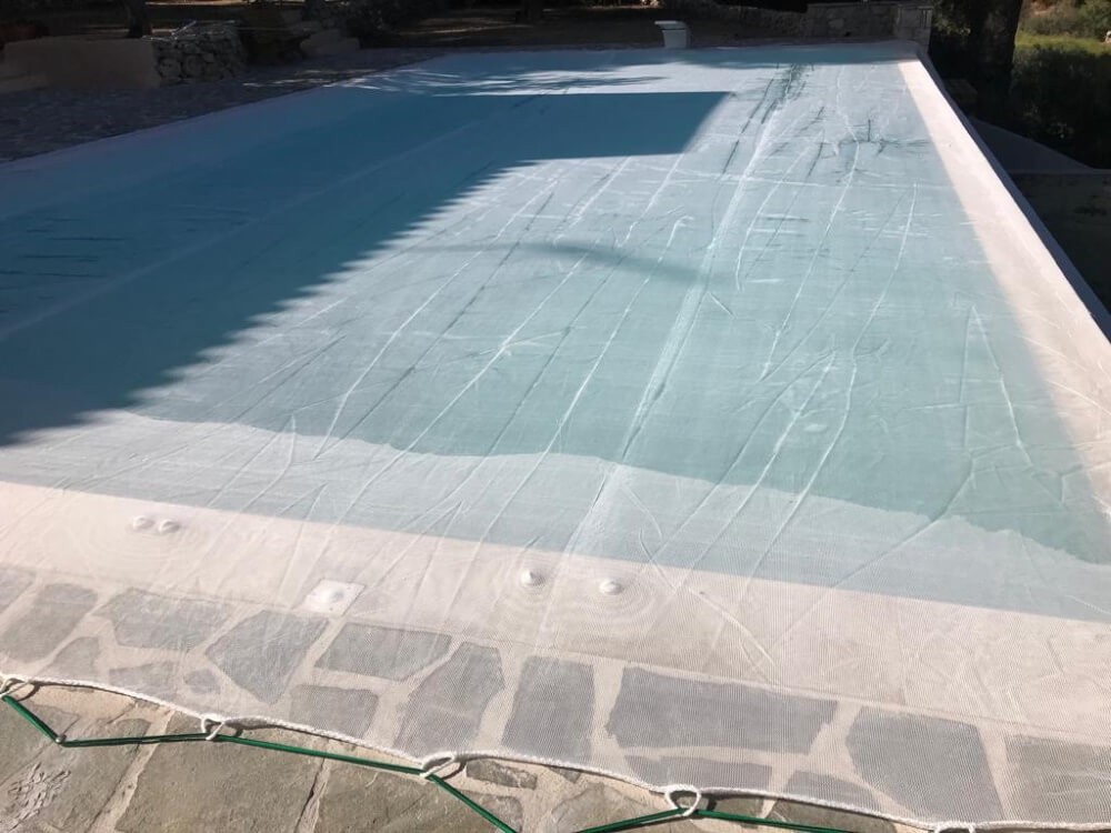 Filet pare-gravats et anti poussière sur une piscine en Grèce