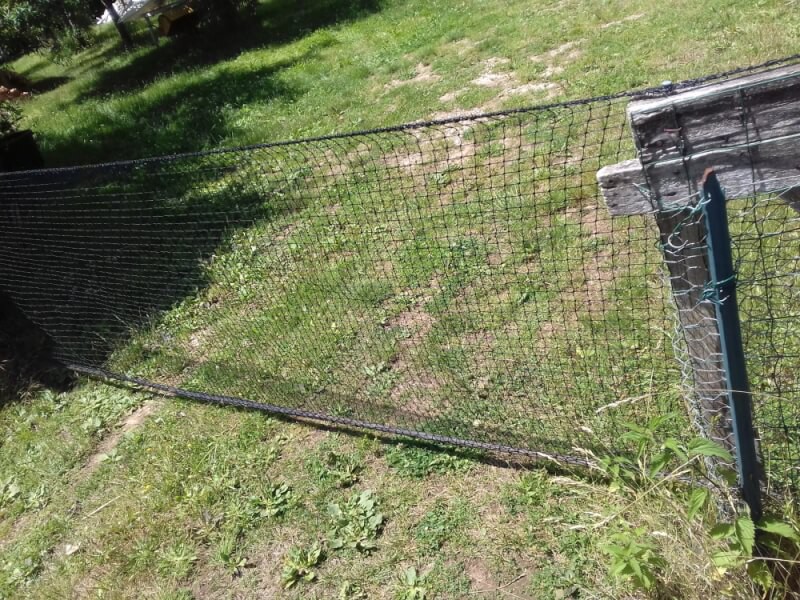 Filet de volière utilisé comme clôture et portail d'entrée sur une propriété privée