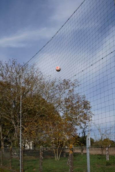 Grand filet pare-ballons installé en bordure de terrain de football